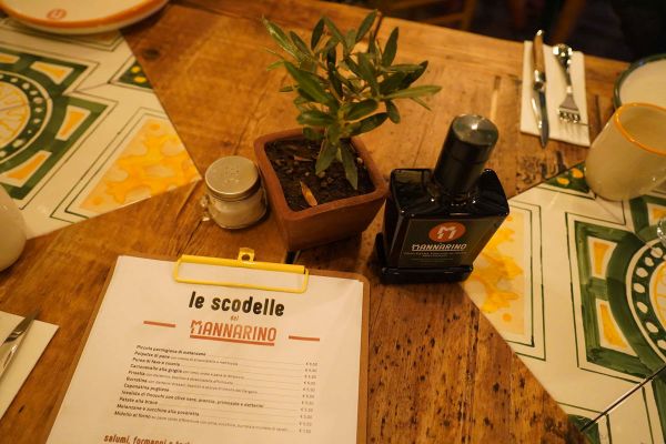 Tavolo da Il Mannarino Milano con menu, olio extravergine e decorazioni.