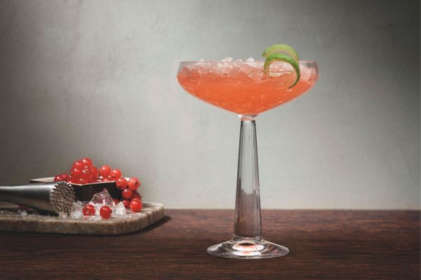 Elegante bicchiere da cocktail Pasabahce Nude. Drink rosa con ghiaccio e lime.