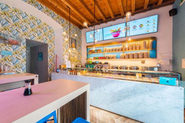 Ristorante moderno con menù digitale e bancone in marmo. Design tropicale, illuminazione calda. Ristorazione innovativa.