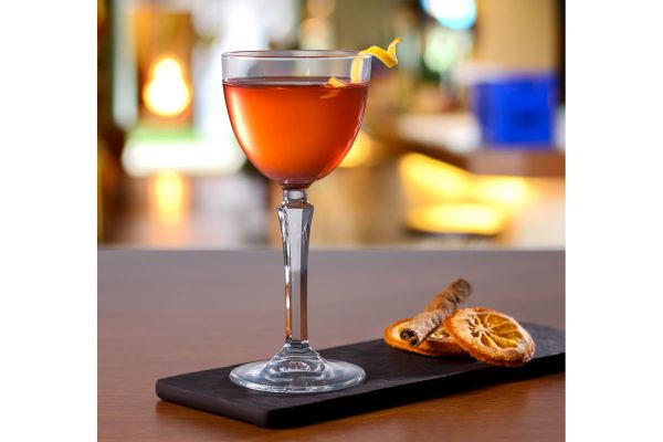 Elegante bicchiere Nude Pasabahce con cocktail Nick & Nora. Decorazioni con arancia e cannella.