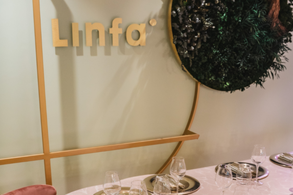 Ristorante Linfa: dettaglio dell'arredamento con logo, parete verde e tavola imbandita. Cucina italiana, Planted.