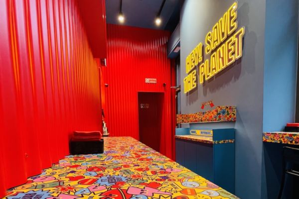 Interni Kebhouze realizzati da Augusto Contract: pareti rosse, bancone colorato, scritta Hey! Save the planet illuminata.