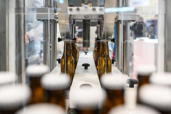 Linea imbottigliamento birra a Beer&Food Attraction. Macchinario riempie bottiglie di vetro ambrato. Fiera settore beverage.