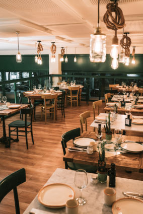 Interno ristorante Il Mannarino: tavoli apparecchiati, lampade rustiche. Design accogliente, atmosfera calda. Cucina tipica pugliese.