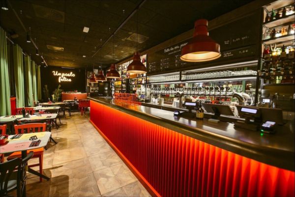 Interno del locale Doppio Malto a Milano Porta Romana: bancone illuminato, tavoli e atmosfera accogliente.