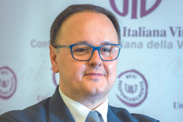 Uomo con occhiali blu, esperto UIV sul rischio vino e Cancer Plan.