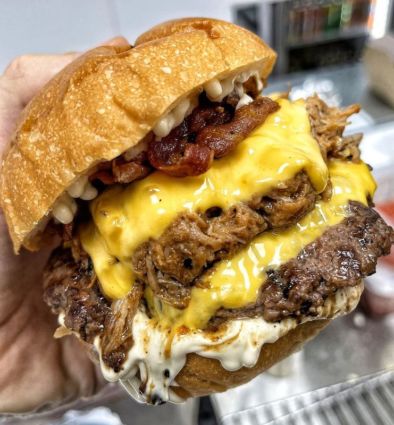 Sbamburger Golocious a Roma: foto ravvicinata di un triplo strato con formaggio fuso, bacon e salse.