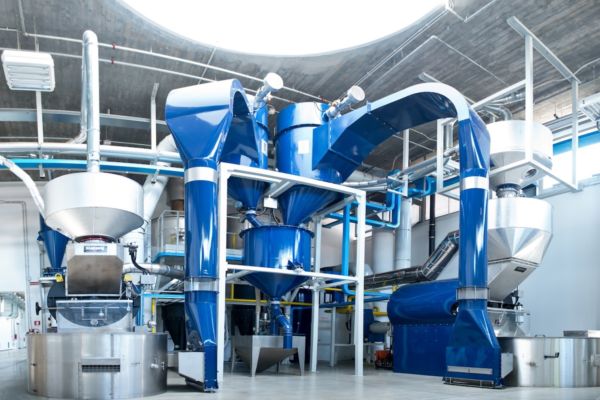 Impianto di produzione caffè Diemme. Macchinari industriali blu e argento. Guerra Ucraina e impatto sul caffè.