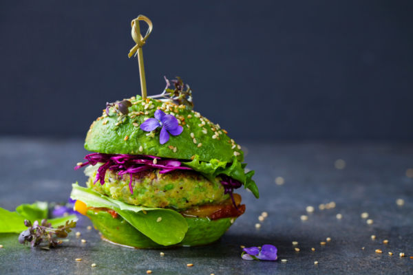 Burgal plant-based di Alain Ducasse: burger vegano con pane verde, cavolo viola e fiore.