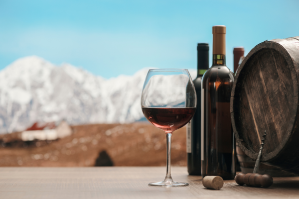 Vino rosso a St. Moritz. Bottiglie, botte e calice con montagne innevate sullo sfondo. Langosteria.