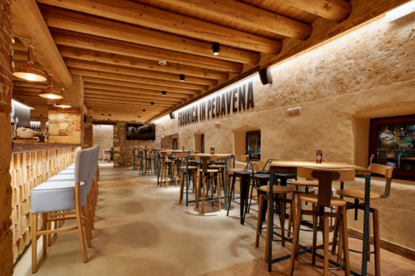 Interni Fabbrica Pedavena Brescia: tavoli, sedie, bancone bar, soffitto in legno. Birreria artigianale.