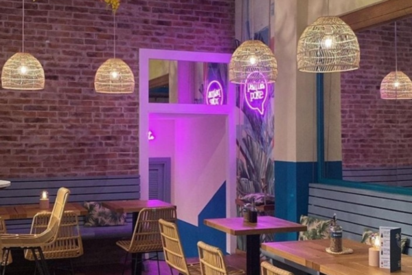 Interno accogliente di Palma Poke. Lampade in vimini, pareti in mattoni e insegna al neon.