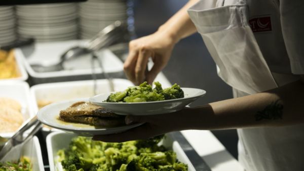 Autogrill e Camst: cuoco prepara piatti in mensa. Broccoli e carne per i dipendenti.