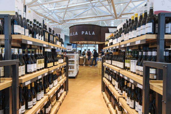 Eataly Fiumicino: scaffali pieni di bottiglie di vino italiano, nuovo punto vendita in aeroporto.