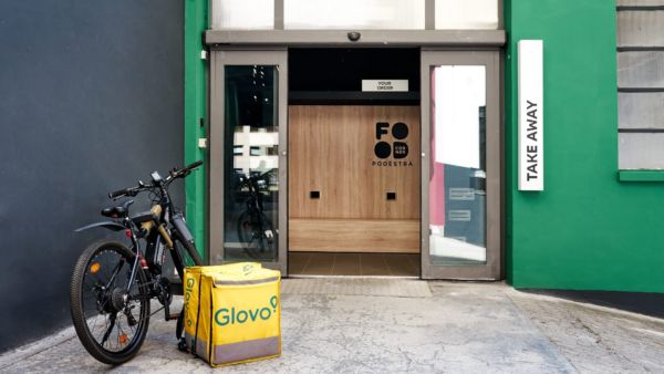 Food corner Glovo a Torino: entrata del locale con bici per il delivery e borsa termica gialla. Take away.