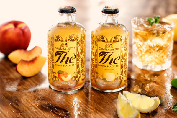 Tè Indian Black Tea San Benedetto pesca e limone. Bottiglie di tè freddo e bicchiere con ghiaccio.