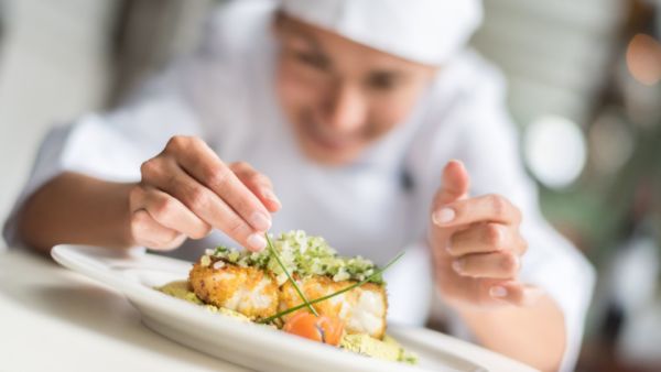 Chef decora piatto di pesce. Serenissima Ristorazione, eccellenza culinaria, Stella Verde.