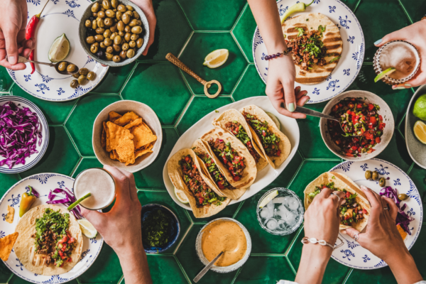Tavola imbandita con Billy tacos Roadhouse, nachos, salse e bevande. GenZ a tavola.