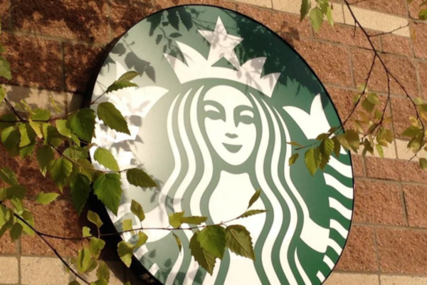 Logo Starbucks su muro, foglie verdi. Community digitale Starbucks, il Third Place.