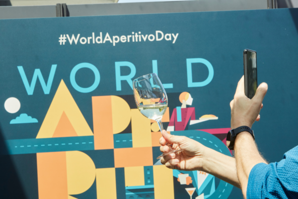 Celebrazione World Aperitivo Day. Calice di vino bianco e smartphone. Evento aperitivo, brindisi e festa.