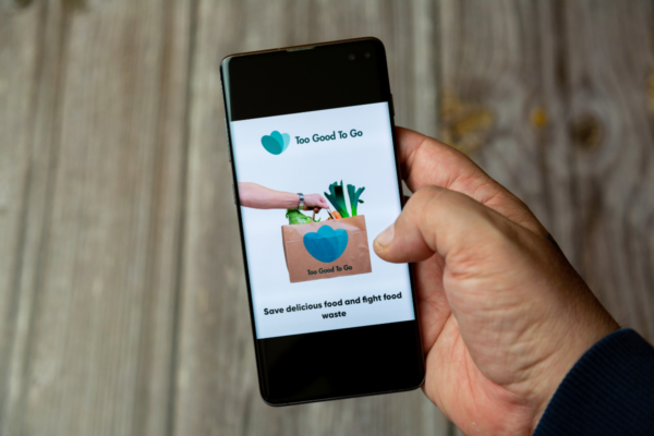Smartphone con app Too Good To Go per sostenibilità alimentare e lotta allo spreco.