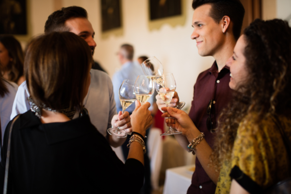 Esportazione vino italiano: brindisi con bollicine. Gruppo di persone celebra il Made in Italy con calici di spumante.
