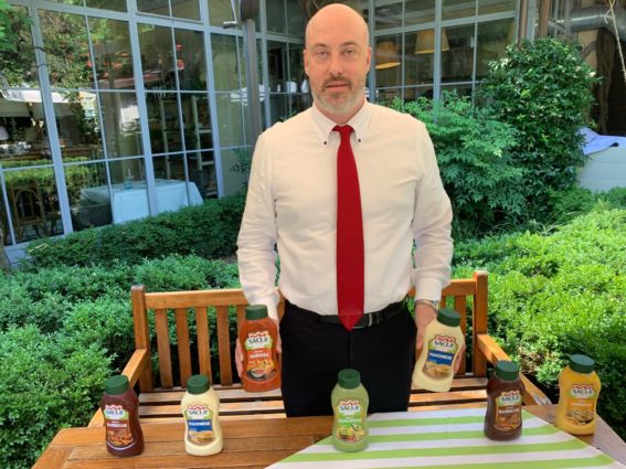 Saclà lancia salse per Horeca. Uomo presenta maionese, barbecue, harissa e guacamole Saclà.