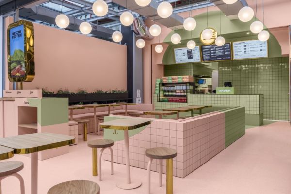 Interni Augusto Contract: design ristorante rosa e verde, illuminazione a globo, tavoli in legno.