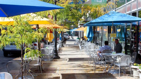 Dehors vivace: tavoli all'aperto con ombrelloni colorati. Arredo urbano per spazi pubblici accoglienti.