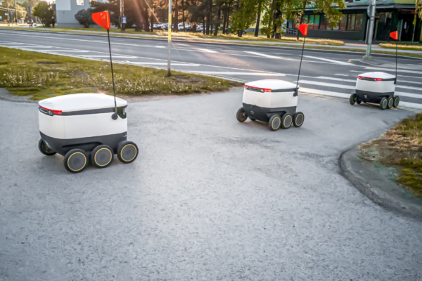 Robot per consegne DoorDash a guida autonoma con bandierine rosse. Veicoli autonomi per delivery.