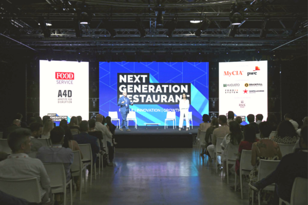 Evento NGR: relatori sul palco, pubblico seduto. Futuro del fuori casa, innovazione ristorazione.