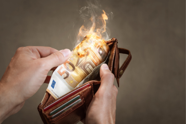 Inflazione USA: banconota da 50 euro che brucia in un portafoglio. Aumento dei prezzi e caro vita.