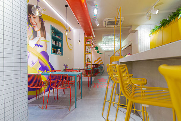 Interni colorati della caffetteria Fluid: murales pop, sedie rosse e sgabelli gialli. Design moderno.