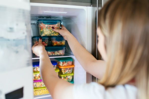 Donna che prende surgelati plant based dal freezer. Alimenti Impossible Foods surgelati.