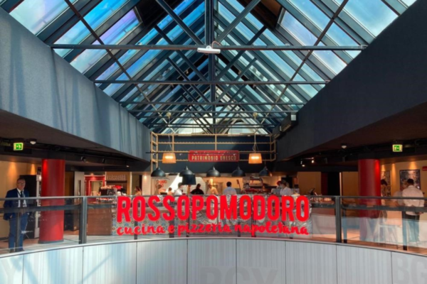 Interni di Rossopomodoro: ristorante, pizzeria napoletana. Design moderno con tetto in vetro e insegna rossa.