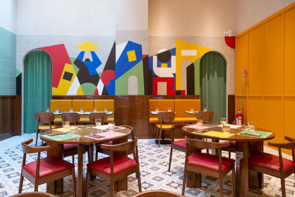 Interni colorati del ristorante Lievità a Milano. Arredi in legno, sedute rosse e murales artistici.