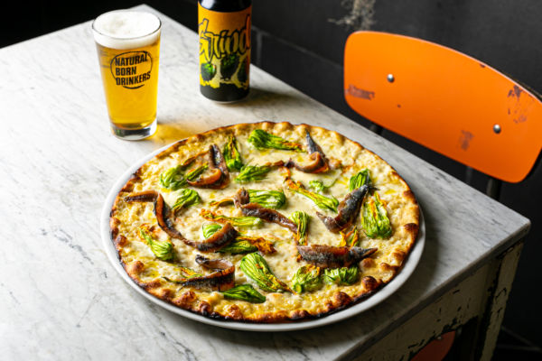 Pizza contemporanea con fiori di zucca e alici. Birra artigianale italiana. Pizzerie d'Italia.