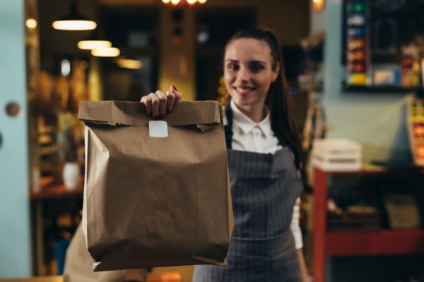 Doggy bag: cameriera sorridente offre sacchetto take away. Ristorante, cibo avanzato.