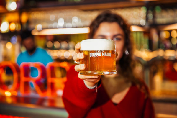 Birra artigianale Doppio Malto. Donna mostra boccale di birra a Parma.