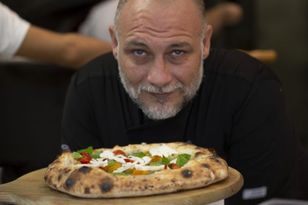 Francesco Martucci, pizzaiolo con pizza gourmet. Pizza con pomodorini, basilico e mozzarella.