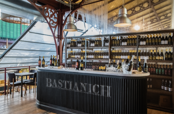 Bar Joe Bastianich a Firenze. Vineria con bottiglie di vino, bancone e illuminazione industriale.