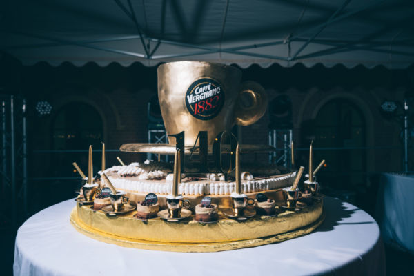 Torta celebrativa Caffè Vergnano 140 anni. Design con tazza dorata e decorazioni a tema caffè.