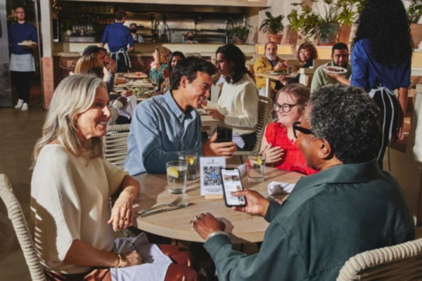 Ristorante con menù digitale tramite QR code su smartphone. Persone a tavola.