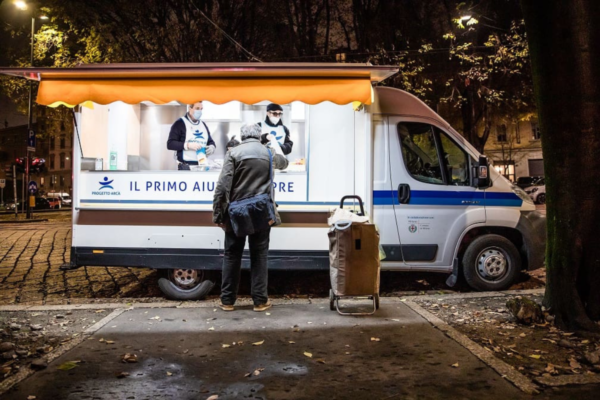 Food truck di Progetto Arca a Milano. Persone ricevono cibo. Aiuto per senzatetto.