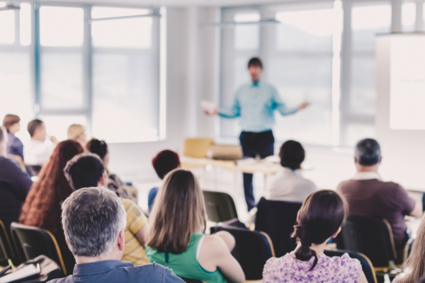Corso Caring on board: persone sedute ascoltano relatore. Aula luminosa, formazione ITS ed Elior.