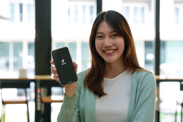Donna sorridente mostra TikTok. Impatto di TikTok sulla ristorazione.