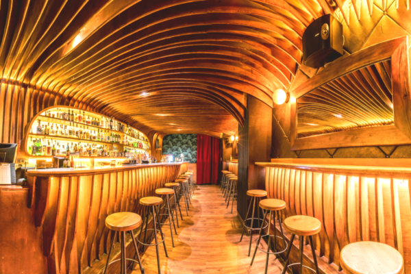Interno bar in legno. Design elegante, illuminazione calda, bottiglie di liquore. The World’s 50 Best Bars.