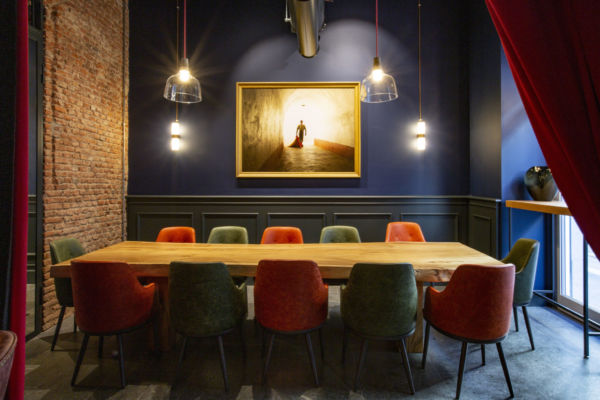 Sala da pranzo Señorío Milano: tavolo in legno massello, sedie colorate, parete blu e mattoni. Cucina iberica.