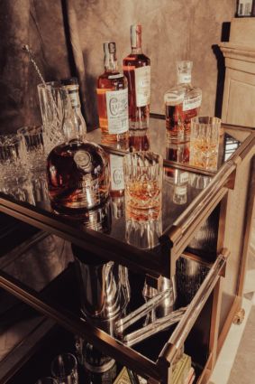 Bottiglie di whisky pregiato e bicchieri su carrello bar. Spirits online in crescita.