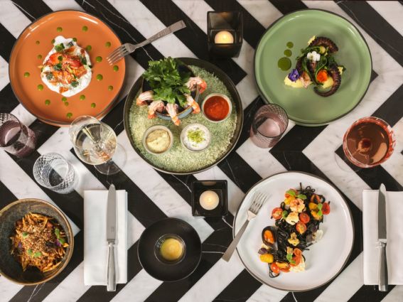 Rivington ristorante: tavolo imbandito con piatti gourmet, frutti di mare, pasta nera e polpo. Cucina newyorkese a Milano.